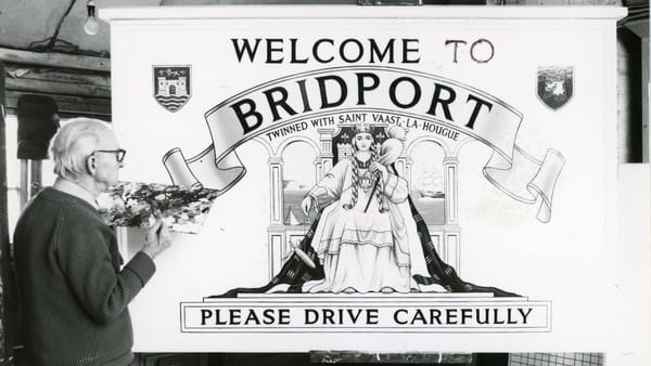 Black and white photo of an elderly man with a painter's palette standing in front of a 'Welcome to Bridport' sign.