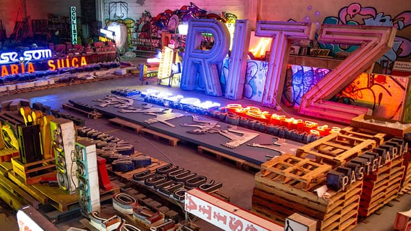 Warehouse space with scores of signs laid out, including many illuminated neon signs.