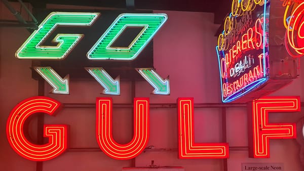 Illuminated neon signs that say 'GO' with arrows below pointing down-right, and 'GULF', among other neon signs.