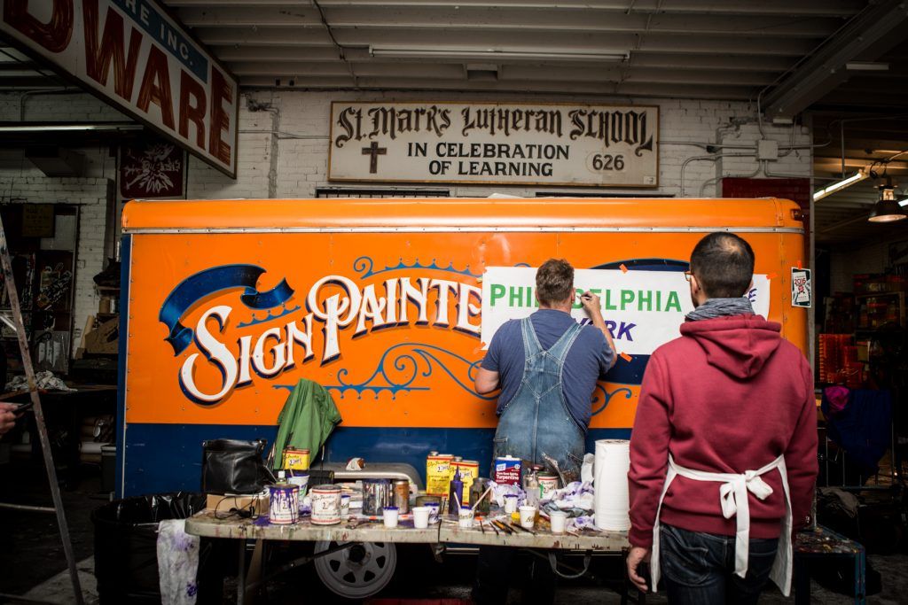 ‘In celebration of learning’ says the sign, Mike Meyer’s hand-lettering workshop in full swing inside Colossal Media / Sky High Murals. (Photo: Christa Lindahl / Colossal Media.)