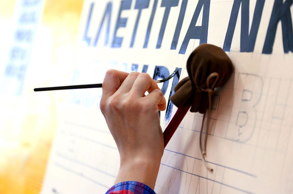 Using a mahl stick to rest the hand on while painting block letters.