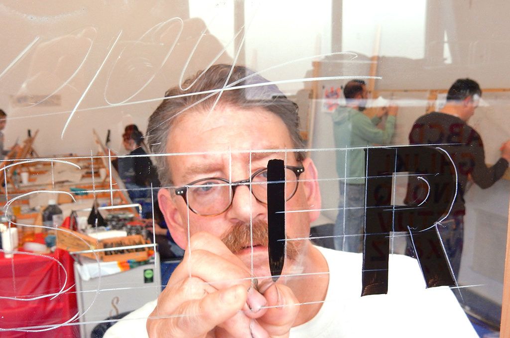 Mike Meyer demonstrating brush technique on some block lettering on glass.