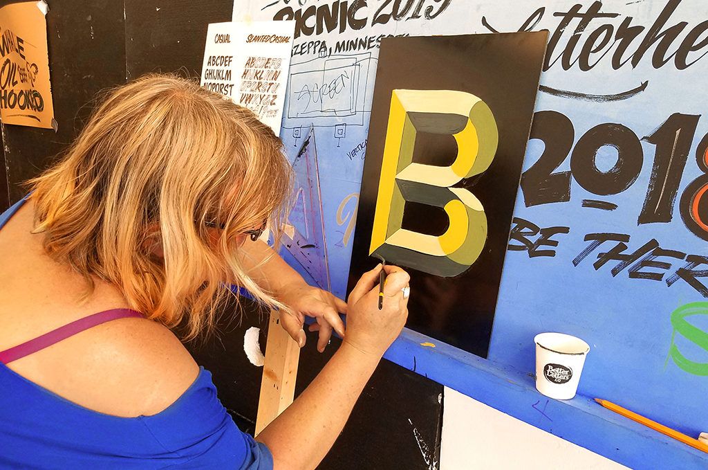 Painting a beveled letter on an aluminium panel.