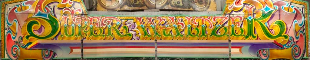 Highly decorated hand-painted fairground lettering that reads 'Super Waltzer'.