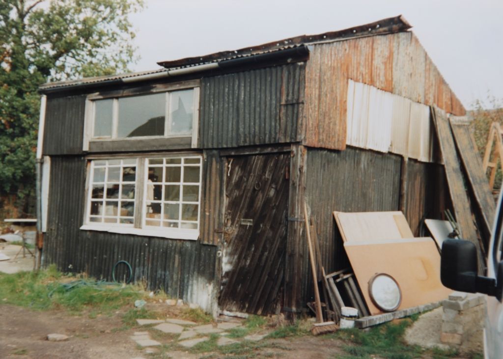 Ramshackle shed made of corrugated iron with scrap metal and timber leaning on the side.