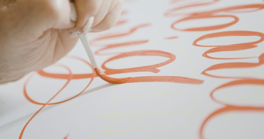 Close-up of brush painting cursive lettering.